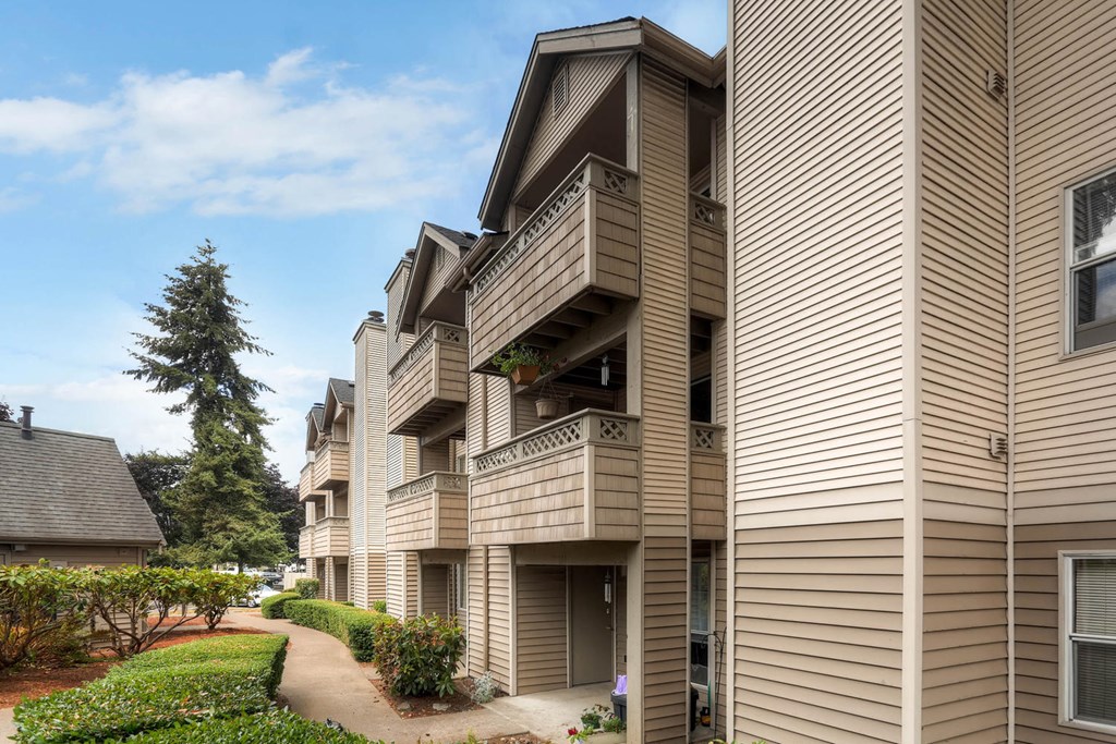 Apartment building with a balcony and a tree in the background.