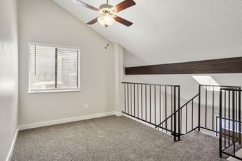 a loft in a home with a ceiling fan and a window  at Hilltop View in Denver, CO