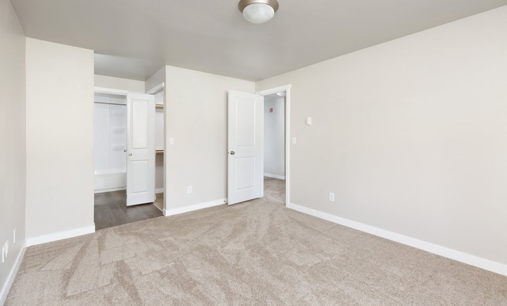 A room with a carpeted floor and two doors.