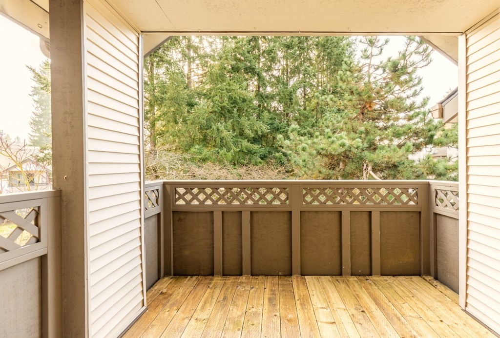 A wooden deck with a railing and trees in the background.