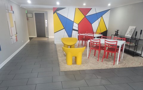a dining room with tables and chairs and a colorful wall
