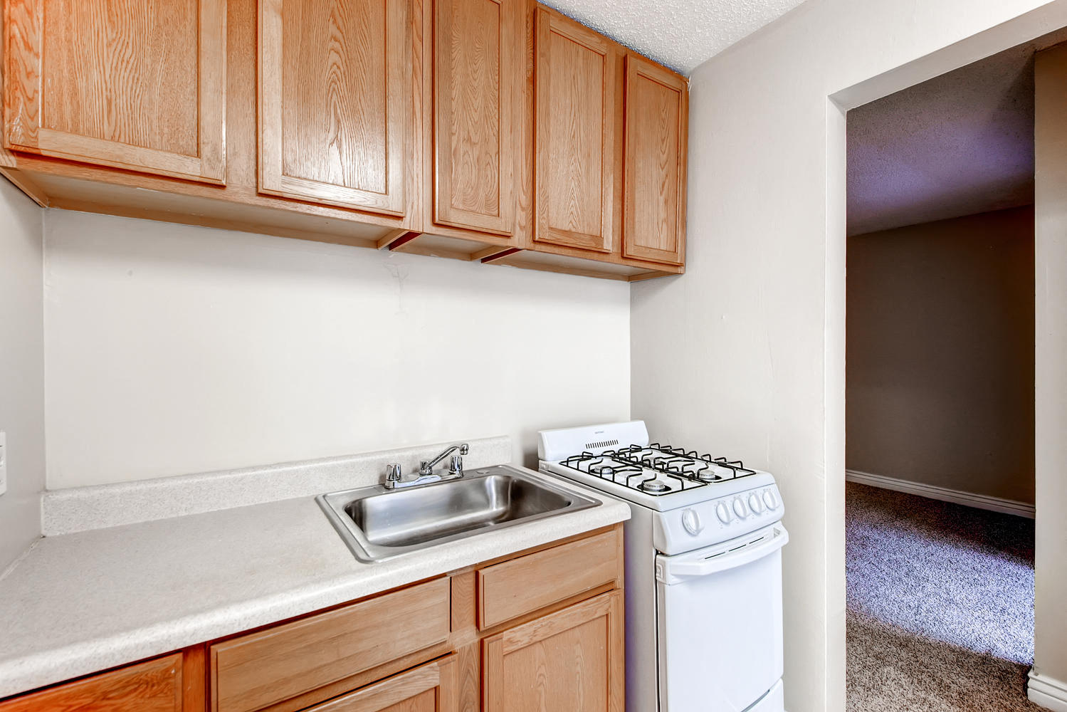 a kitchen with a stove and sink and wooden cabinets