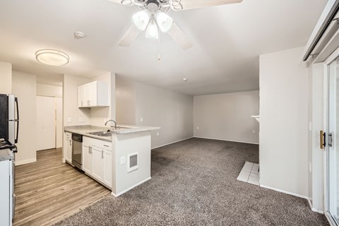 A spacious kitchen with white cabinets and a ceiling fan.