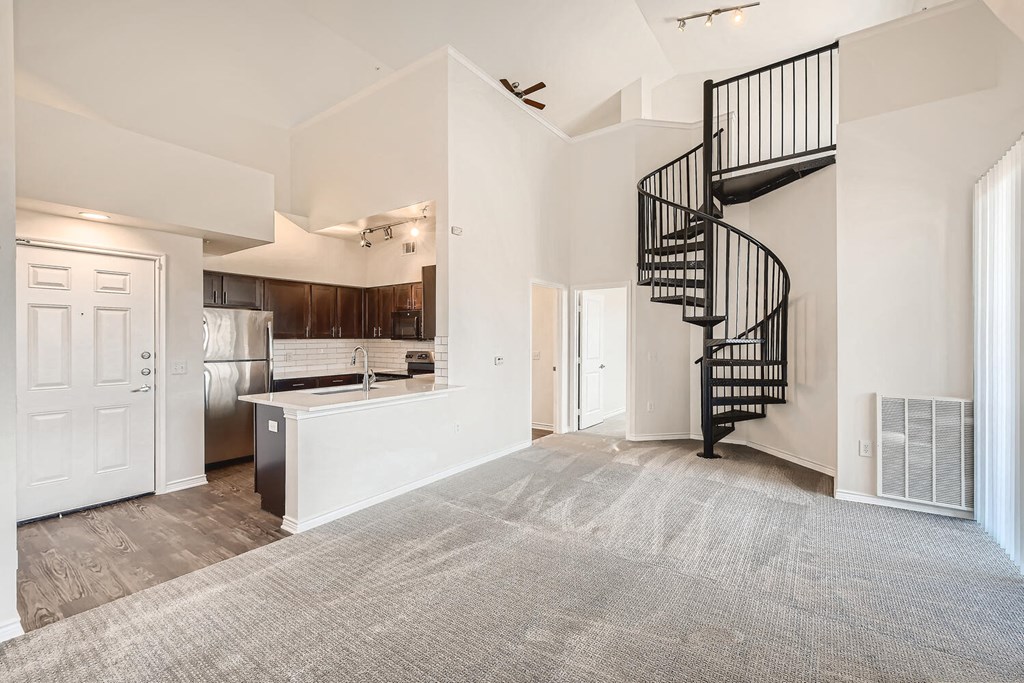 A Living Room and Kitchen with a Spiral Staircase at Fox Run Lofts Apartments