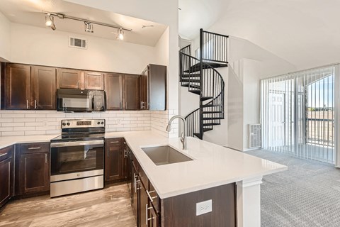 a kitchen with a sink and a stove and a spiral staircase