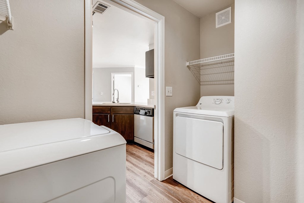 A washer and dryer in a laundry room with a door to a kitchen at Eagles Landing Apartments