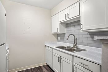 a kitchen with white cabinets and a stainless steel sink and dishwasher  at Hilltop View in Denver, CO