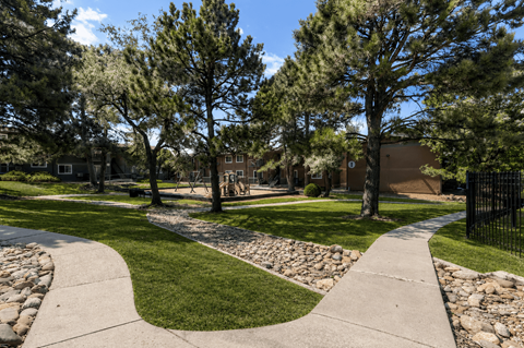 A walkway with grassy areas and trees in front of a building.