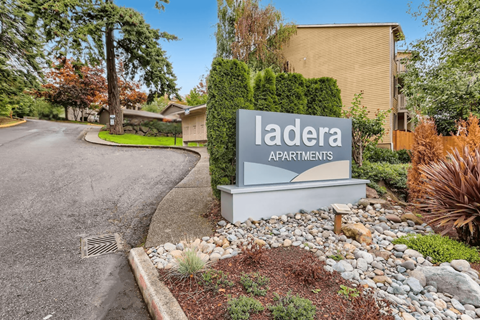 A sign for Ladera Apartments is in front of a building.