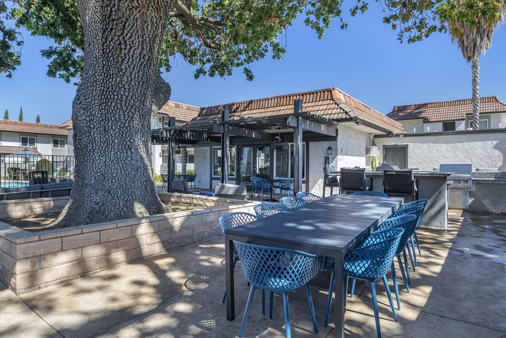 a patio with a table and chairs and a large tree at Sage Creek Apartment Homes, Simi Valley, CA