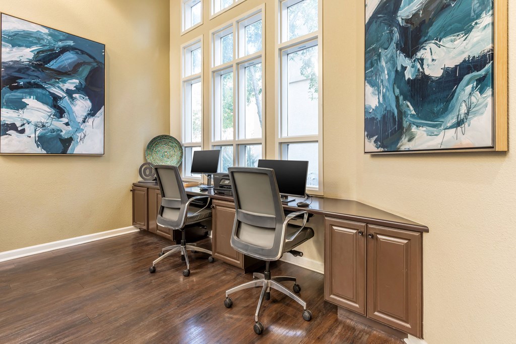 a home office with desks and chairs and windows