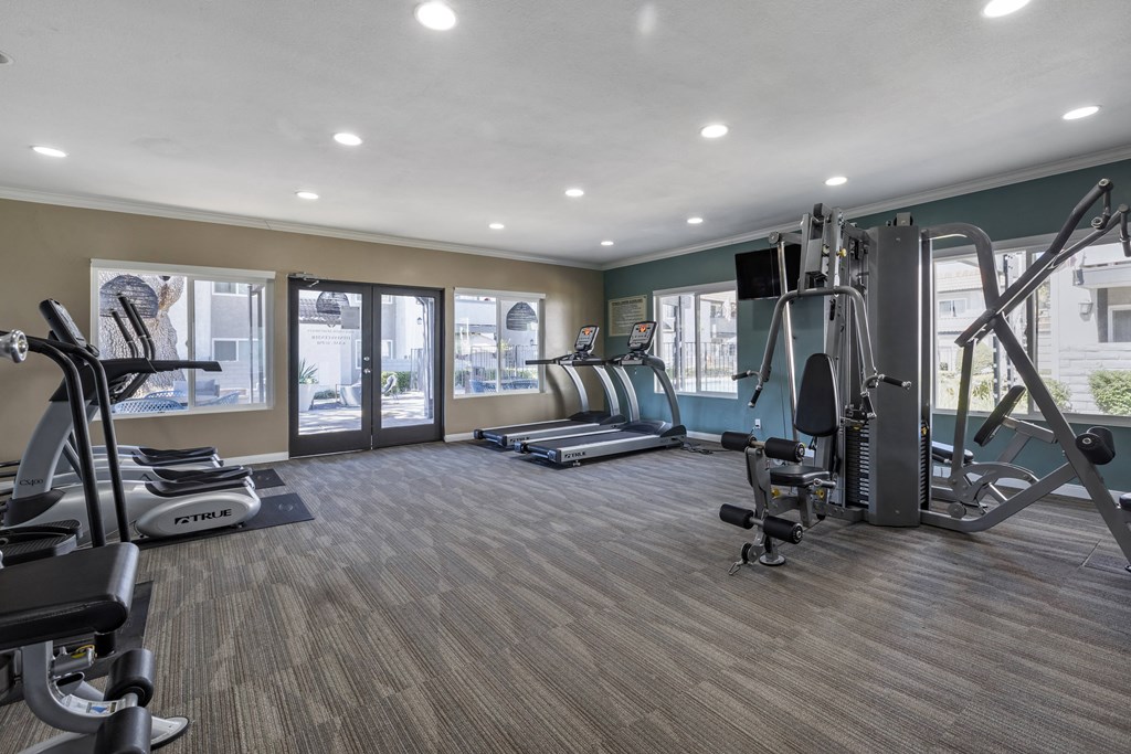 a gym with cardio equipment and windows at Sage Creek Apartment Homes, California