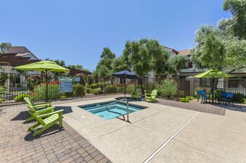 a swimming pool with green chairs and umbrellas in front of a house at Trevi Apartment Homes, Chandler, Arizona