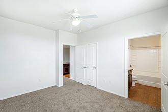 a bedroom with white walls and a ceiling fan