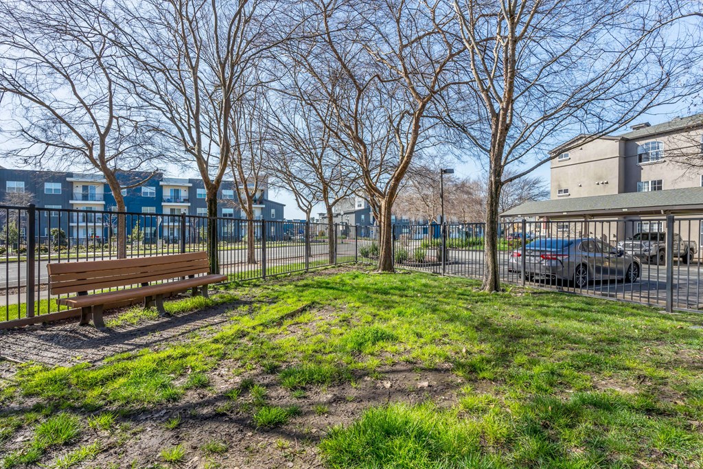 a park with a bench and a fence in front of a building