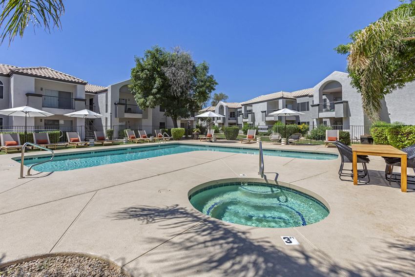a swimming pool with a hot tub and tables and chairs with umbrellas in the background - Photo Gallery