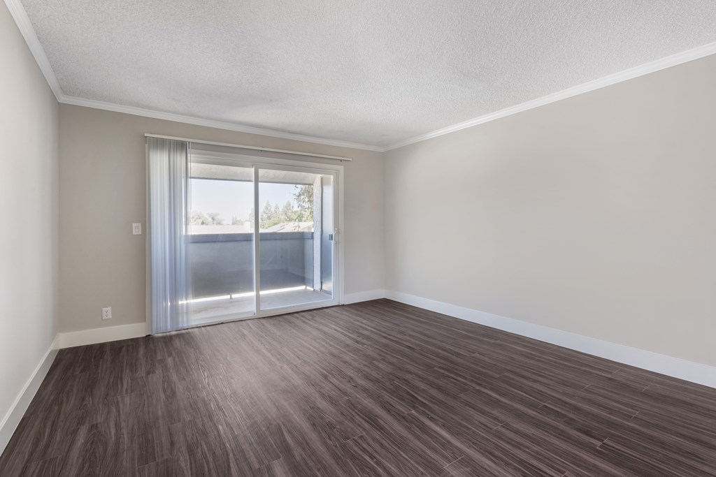 a bedroom with a sliding glass door and hardwood floors at Sage Creek Apartment Homes, Simi Valley, CA 93063