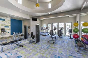 a gym with cardio equipment and weights in a large room with windows at Trevi Apartment Homes, Chandler, AZ, 85224