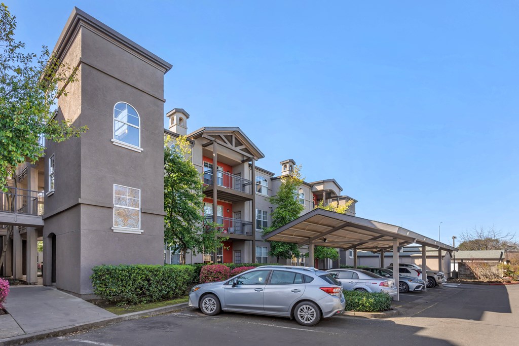 a parking lot with cars parked in front of an apartment building