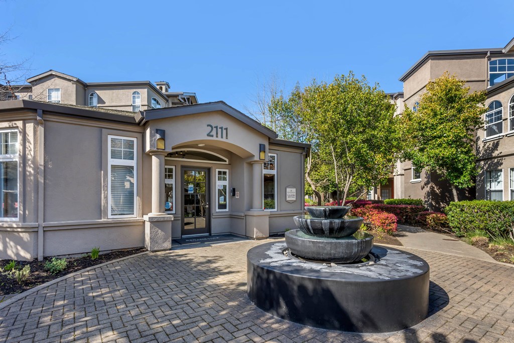 a fountain in front of a house with a front door