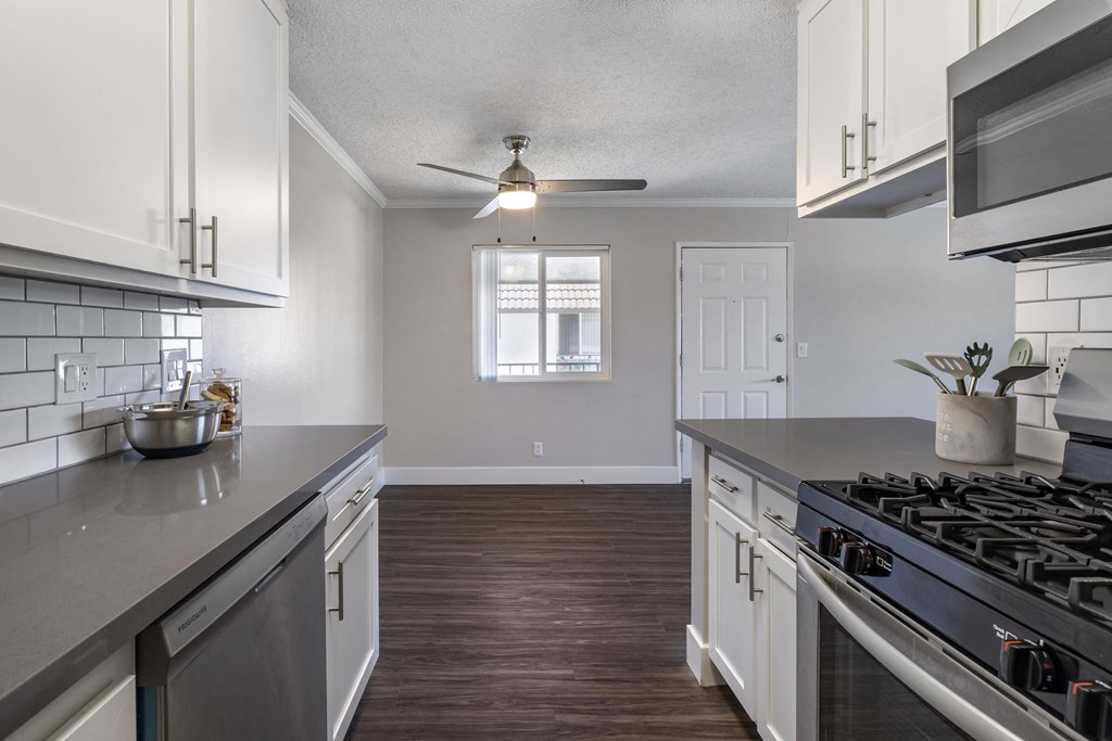 a kitchen with white cabinets and gray countertops at Sage Creek Apartment Homes, California