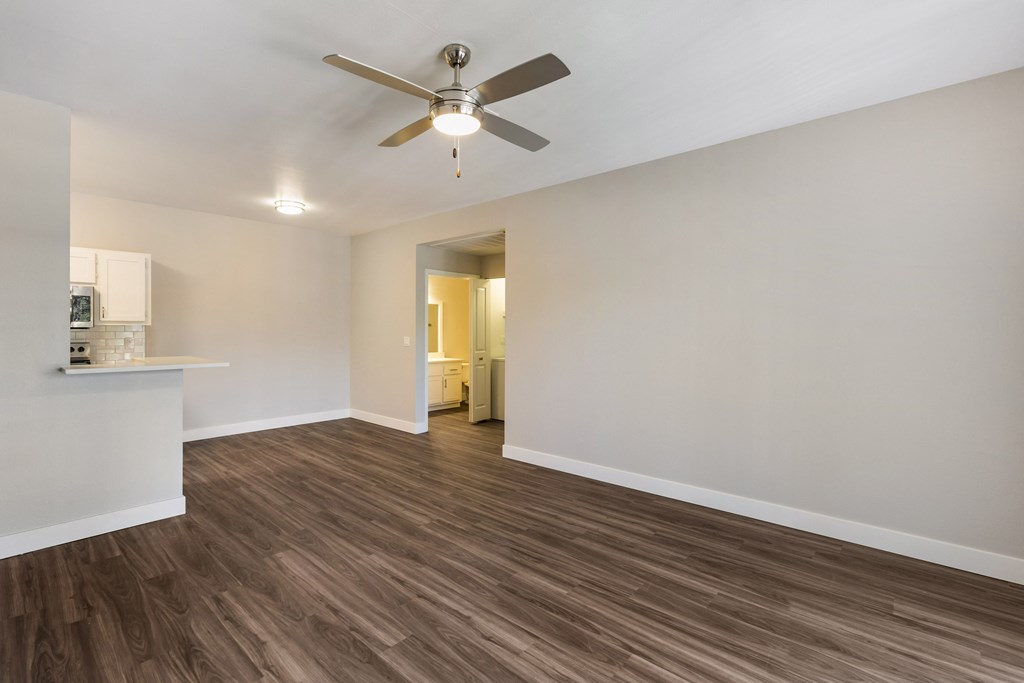 Experience cozy comfort in our living room, complete with a gentle ceiling fan overhead and a glimpse of our stylish kitchen in the background at Boulders at Lookout Mountain Apartment Homes, Phoenix,