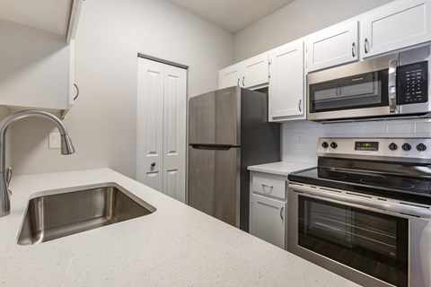 Experience culinary bliss in our sleek kitchen adorned with pristine white cabinets and modern stainless steel appliances