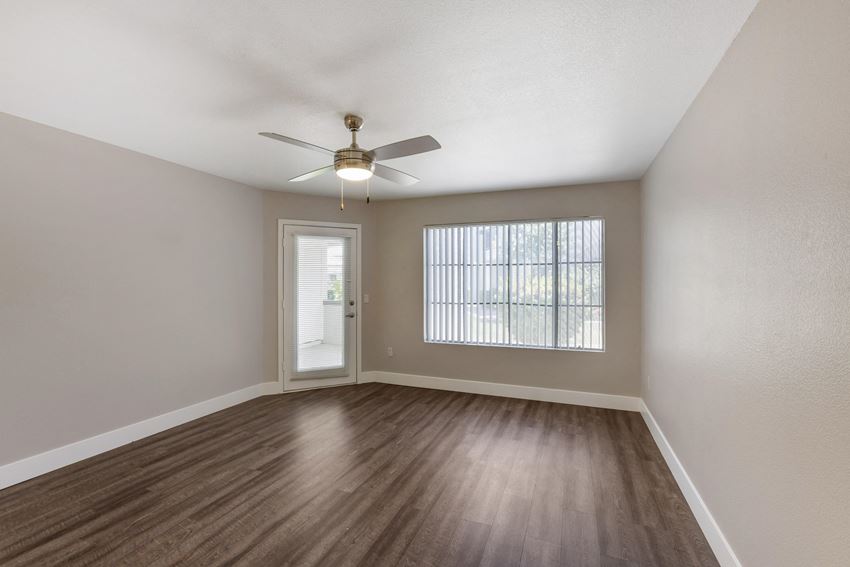 an empty living room with a ceiling fan and a window - Photo Gallery