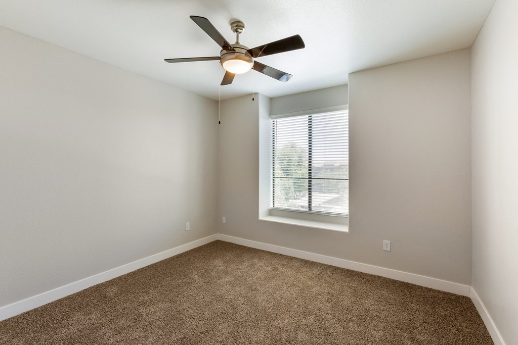 Relax in this serene bedroom with a ceiling fan and sunlit window at Trevi Apartment Homes, Chandler, AZ