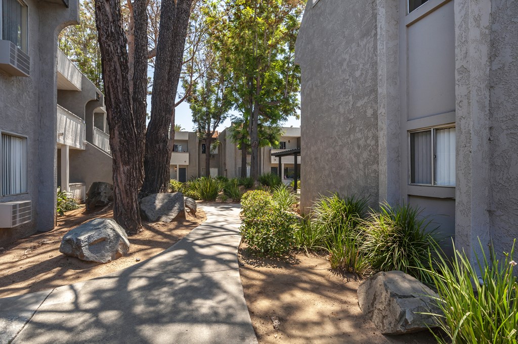 a walkway between two buildings with trees in the background at Scripps Poway Villas, California, 92064