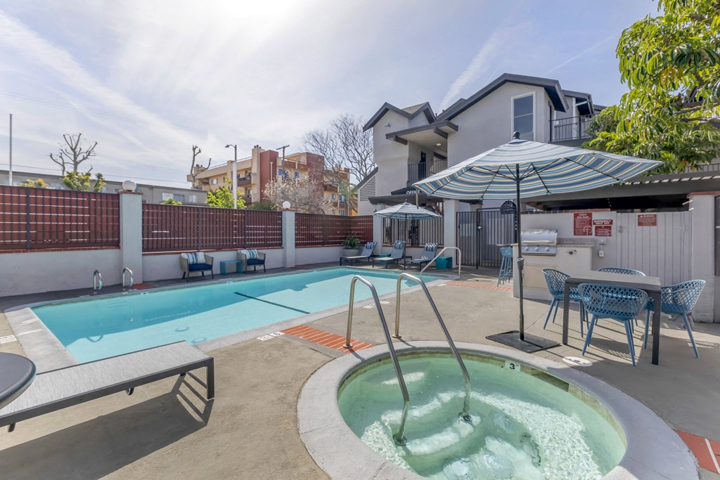 our apartments have a pool and a patio with chairs and an umbrella