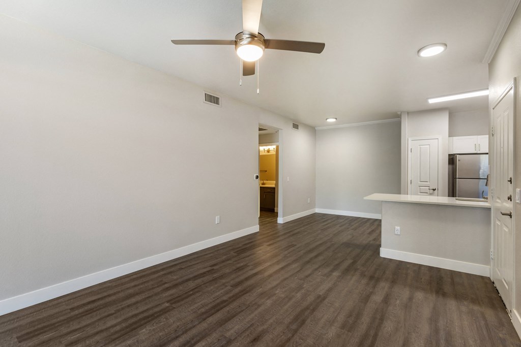 An airy living room beckons with a tranquil ceiling fan, while the kitchen beyond hints at culinary adventures at Trevi Apartment Homes, Arizona, 85224