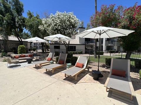 a patio with lounge chairs and umbrellas in a courtyard