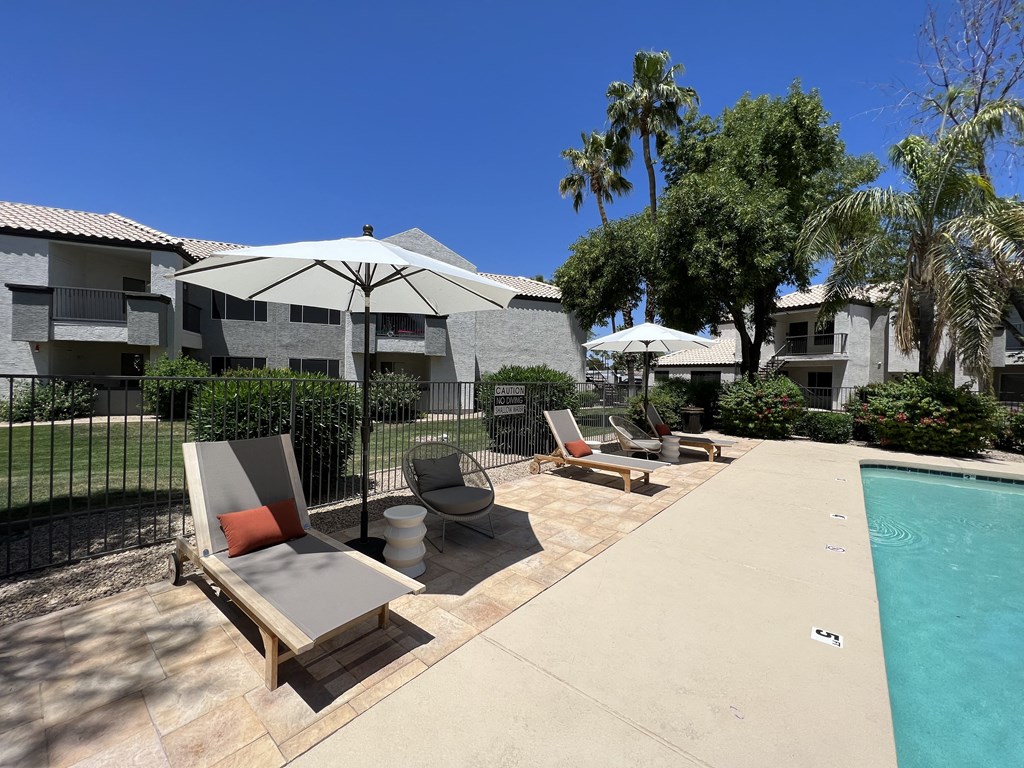 Dive into relaxation in our backyard paradise. Enjoy poolside comfort with chic chairs and shady umbrellas at Boulders at Lookout Mountain Apartment Homes, Arizona