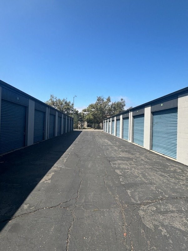 A long, empty parking lot with a clear blue sky above.