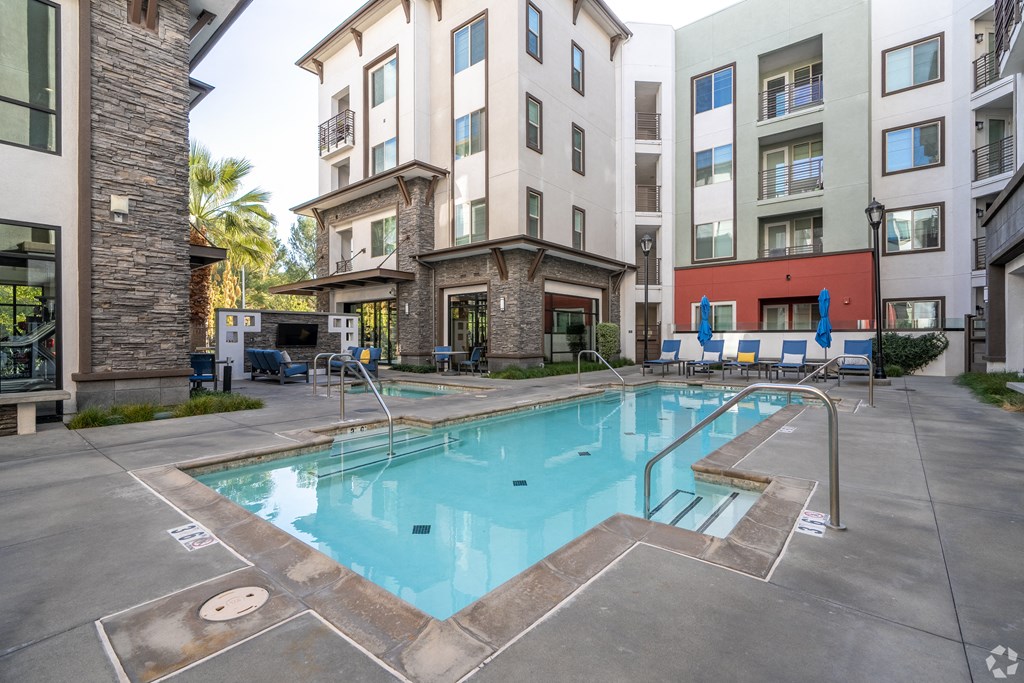 A swimming pool surrounded by buildings and chairs.