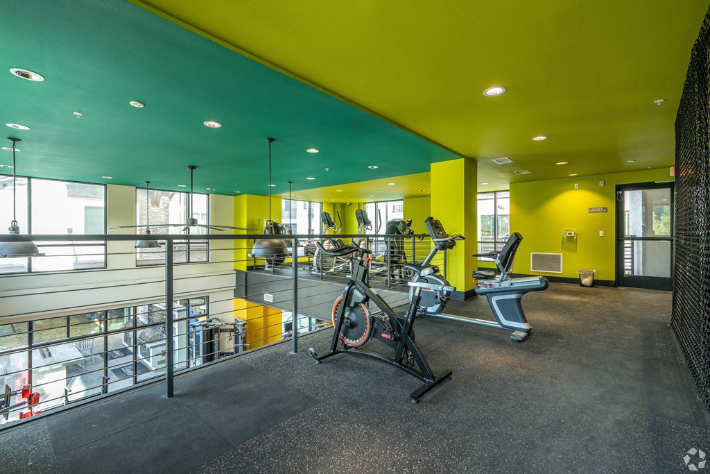 A gym with a yellow wall and a treadmill.
