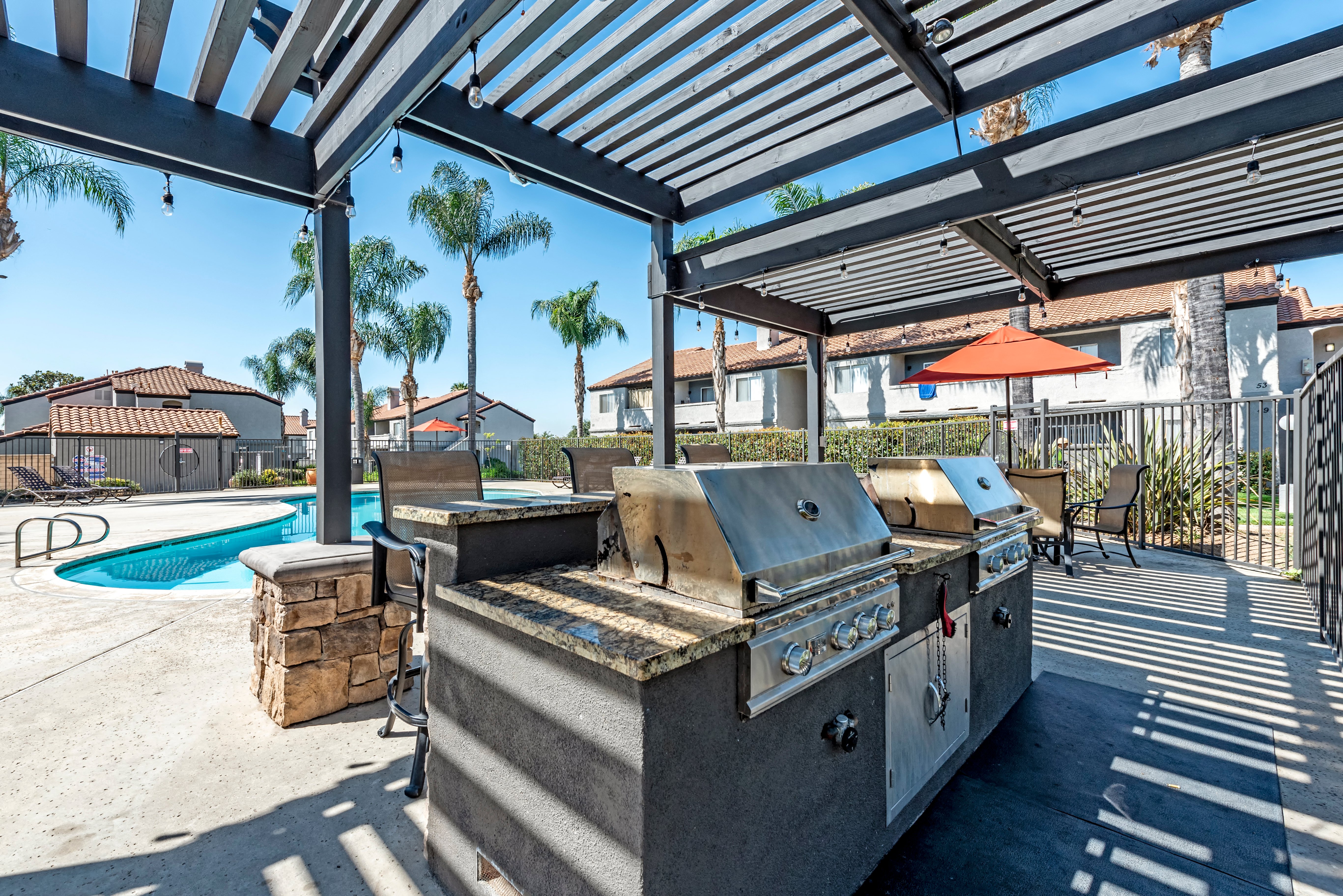 the outdoor kitchen has an outdoor grill and a pool