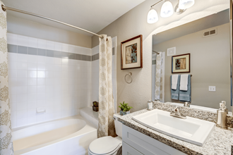 2 BR Apartments in Spring Valley NV - Aviara - Modern Bathroom with a Mirror, a Toilet, Granite Countertops with a Sink, and Tile Walls in the Shower