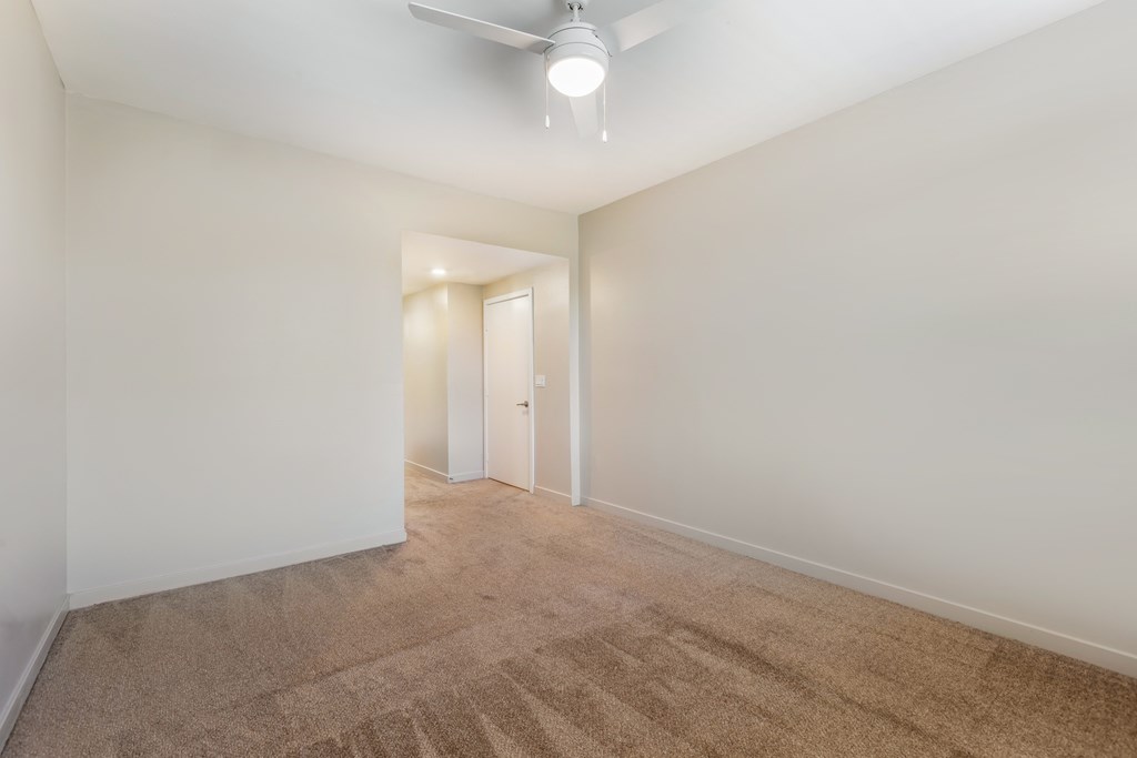 a living room with white walls and carpet and a ceiling fan at Metro Gateway, Riverside, 92503