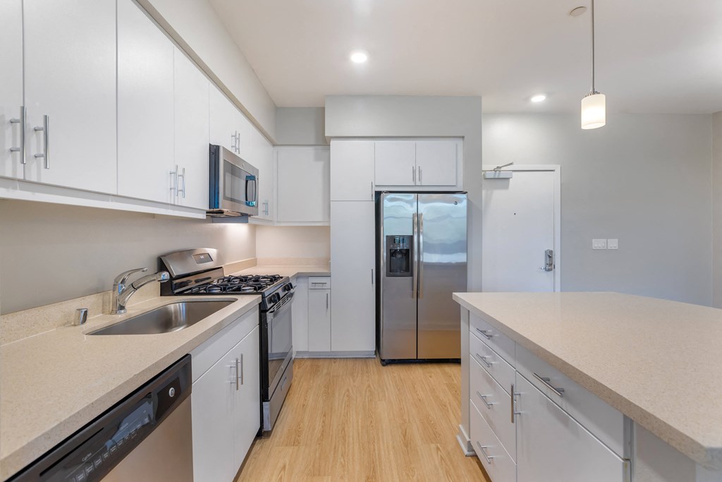 a kitchen with white cabinets and a stainless steel refrigerator at Metro Gateway, California