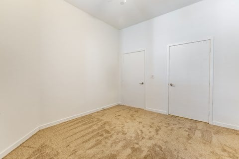 a bedroom with white walls and carpet and two doors