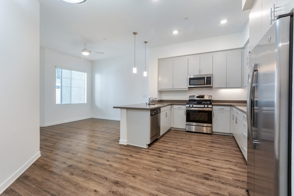 an empty kitchen with white cabinets and stainless steel appliances at Metro Gateway, Riverside, CA