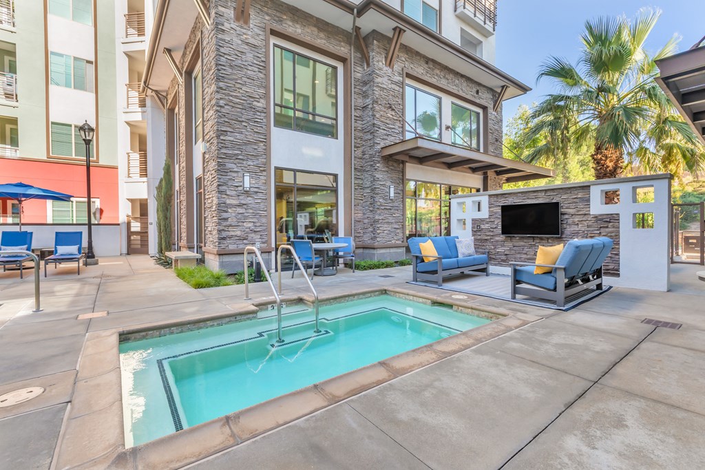 a swimming pool with chairs and a building with a fireplace at Metro Gateway, Riverside, CA, 92503