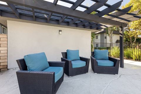 an outdoor patio with chairs and a pergola
