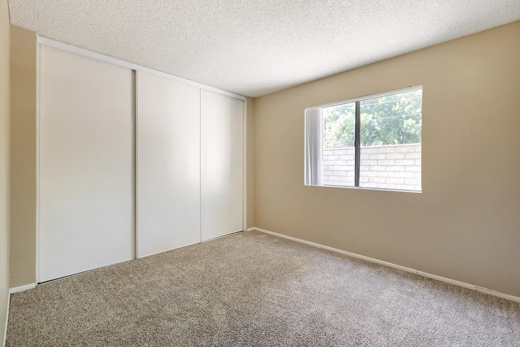 an empty room with white cabinets and a window