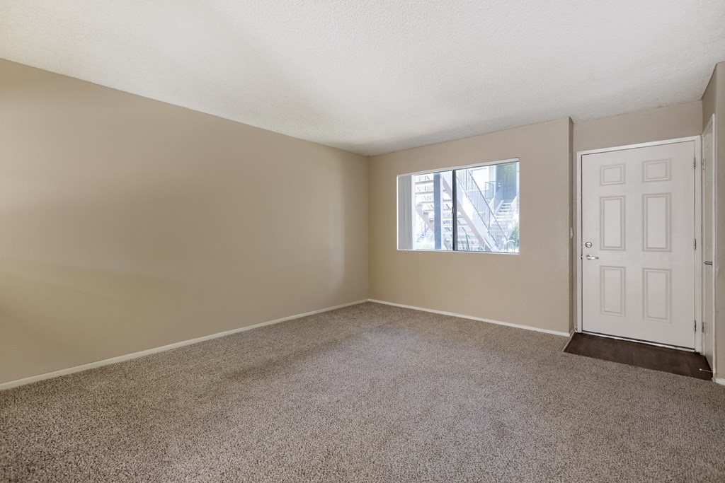an empty living room with carpet and a white door