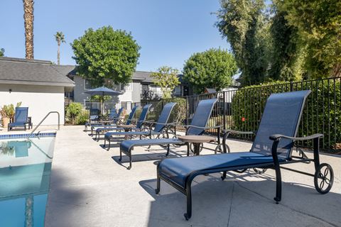 a group of lounge chairs on a patio next to a pool