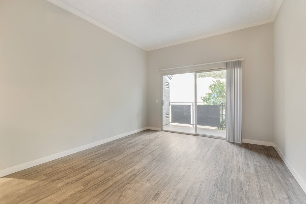 an empty living room with wood floors and a sliding glass door