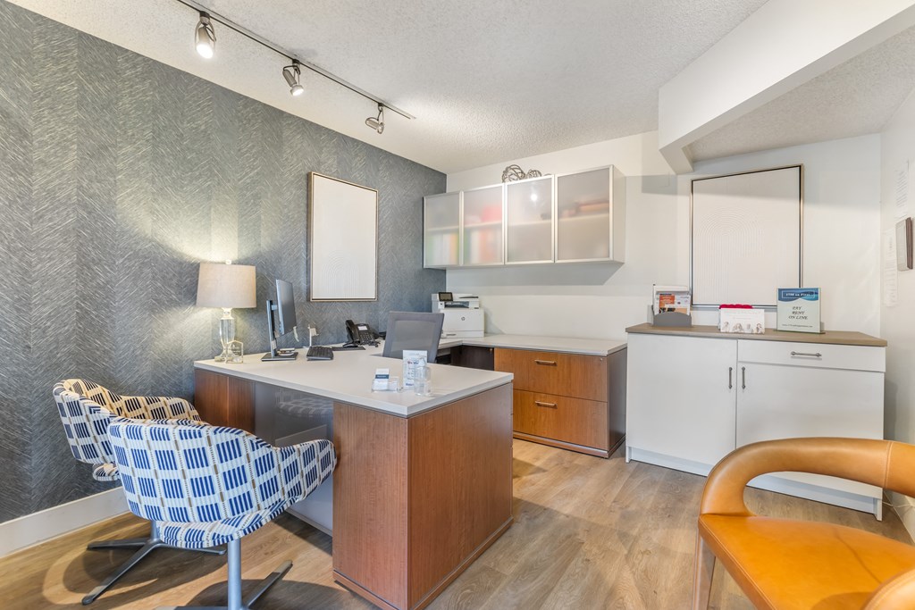 an office with a desk and a chair and a kitchen